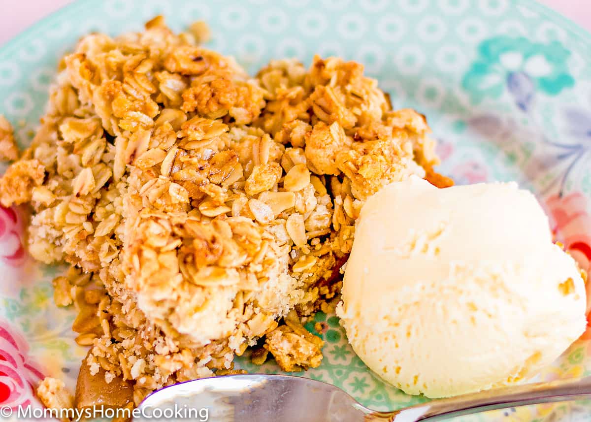 Eggless Apple Crumble with Oats with a ball of ice cream in a blue plate with a spoon