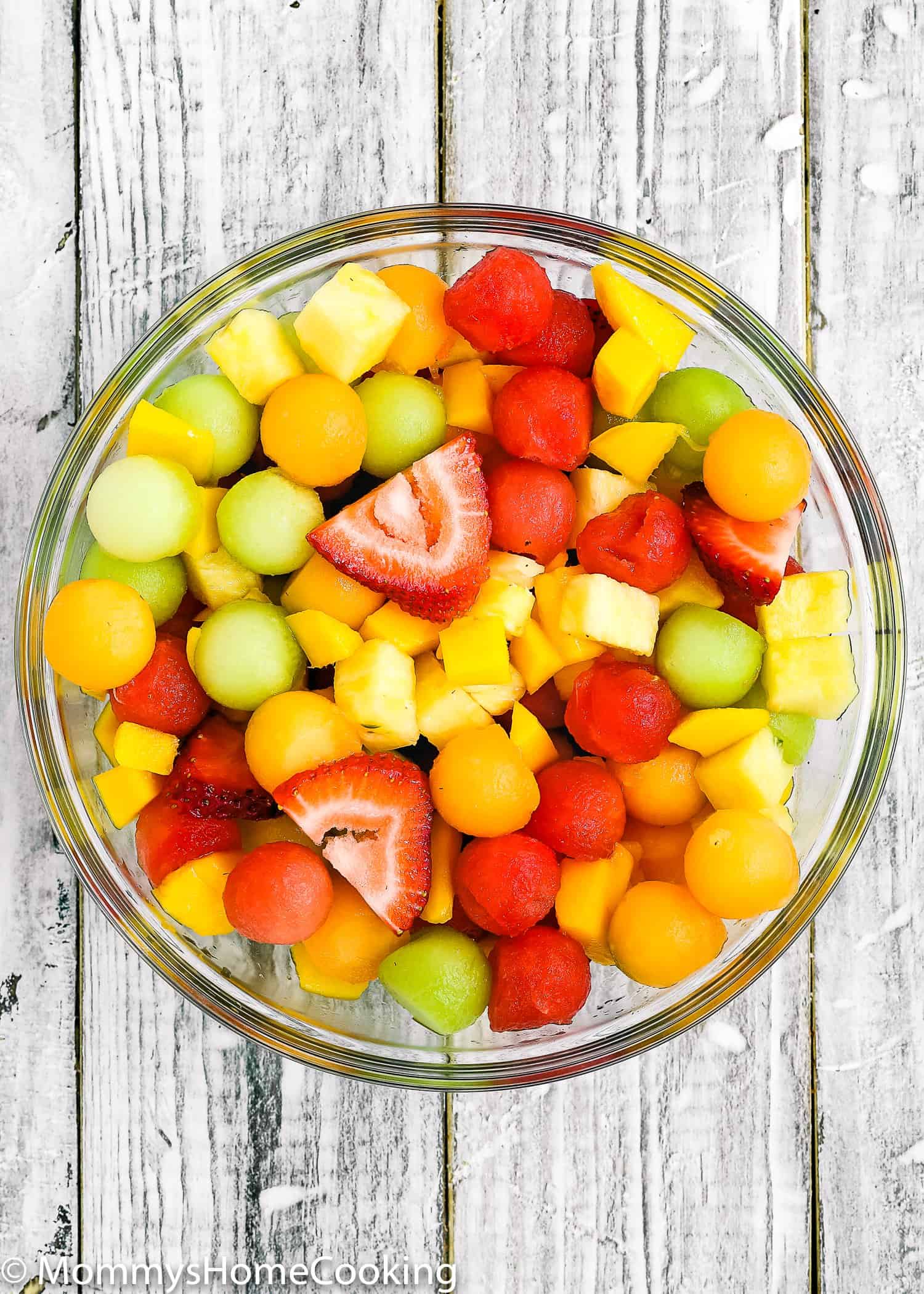 a glass bowl filled with chopped fresh fruit.