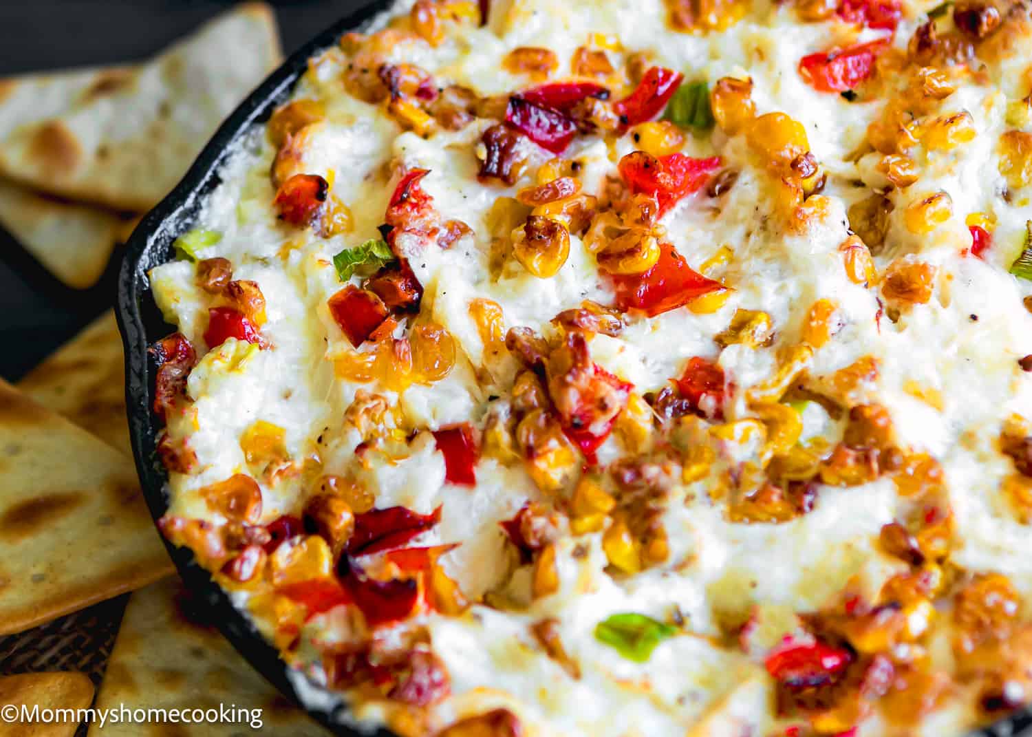 baked crab dip with roasted veggies in a cast iron skillet.