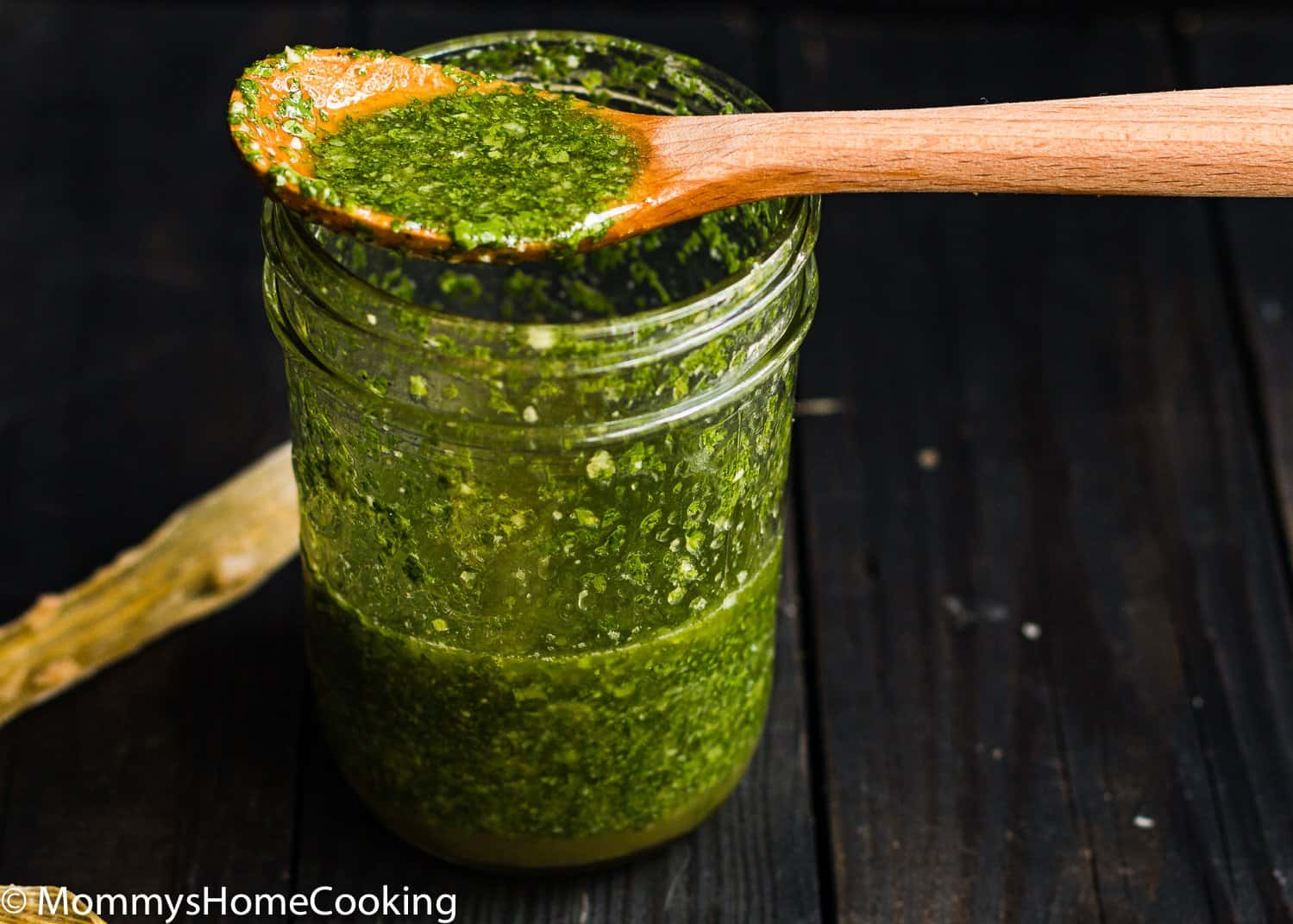 cilantro mojo in a jar with a wooden spoon.