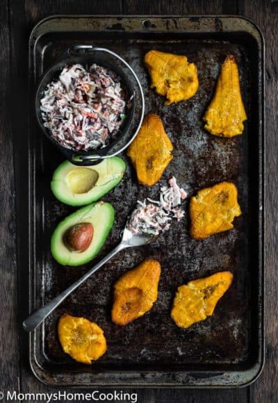 fried tostones in a baking sheet with coleslaw and avocado