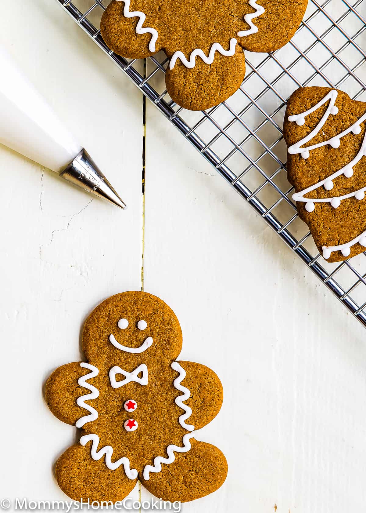 Eggless Gingerbread man Cookie over a wooden surface with a piping bag with eggless royal icing in it