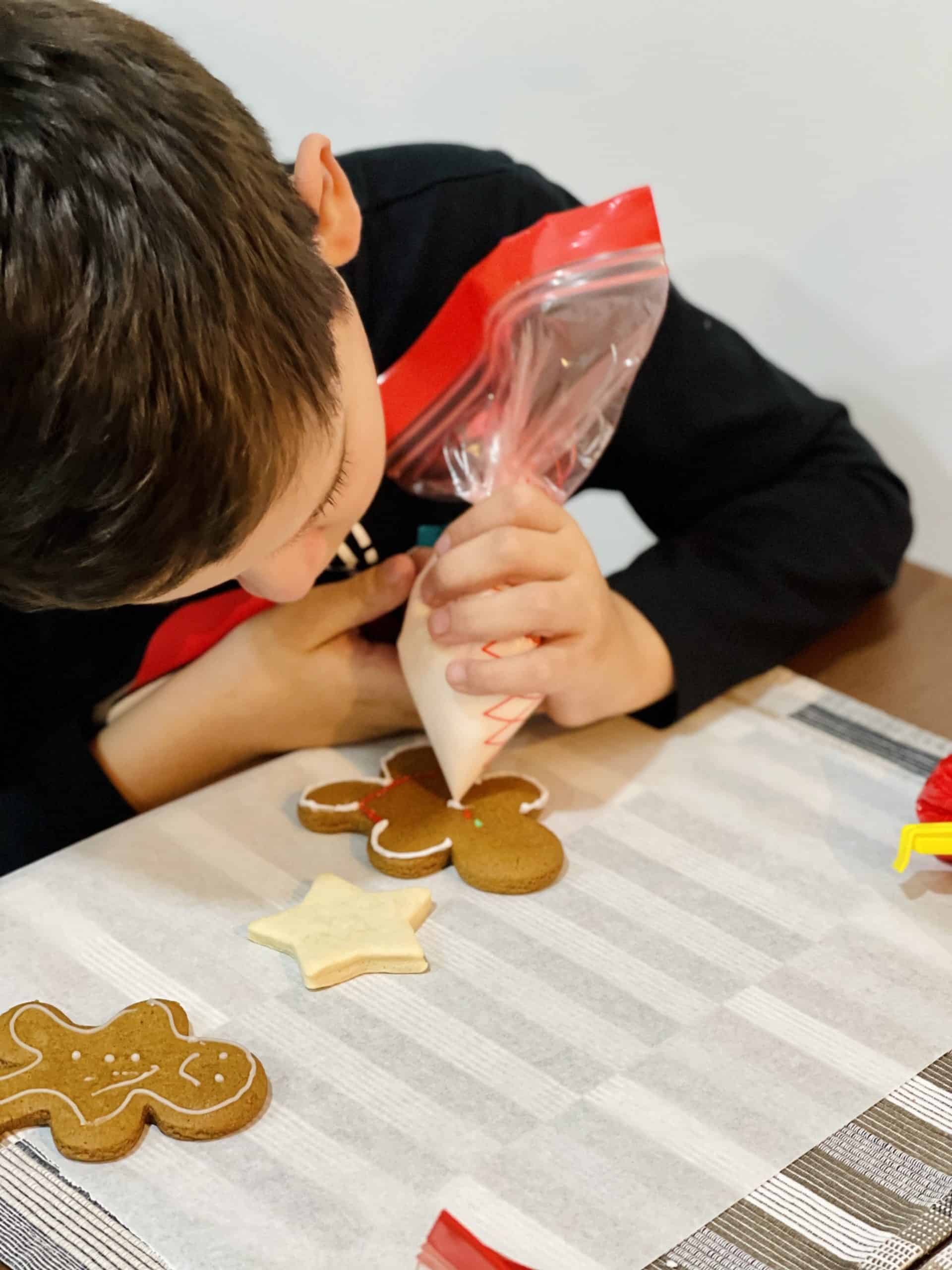 a little boy decorating egg-free gingerbread cookie. 