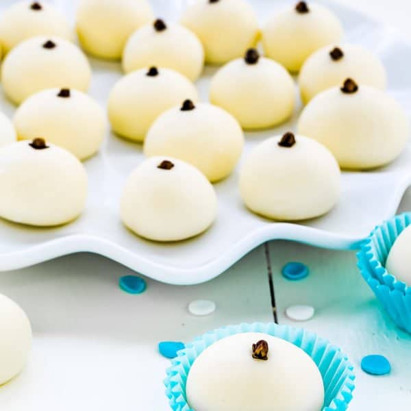 A platter of milk truffles (milk truffles) with a clove on top on a serving platter.