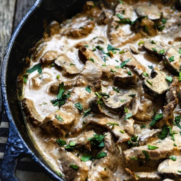 A skillet brimming with Easy Beef Stroganoff, showcasing sliced beef and mushrooms bathed in a creamy sauce, all garnished with chopped parsley.