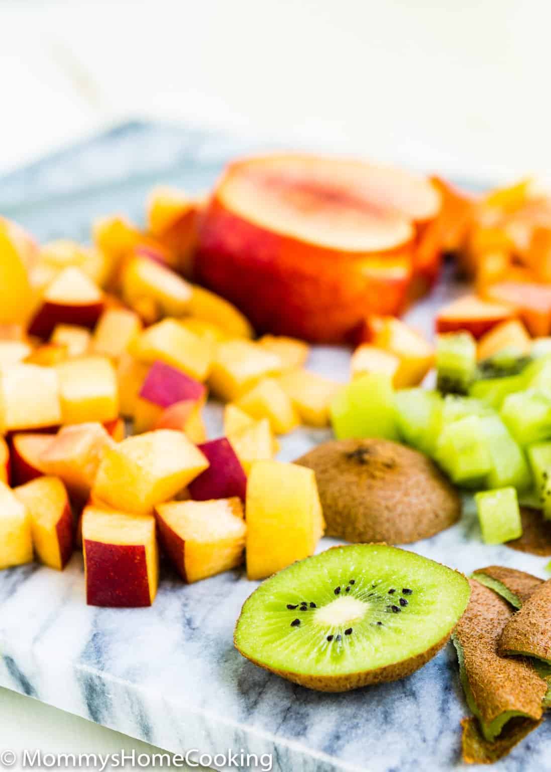 Chopped peaches and kiwifruit, with some slices and peels, arranged on a marble cutting board—perfect for adding to an Easy Fruity White Sangria.