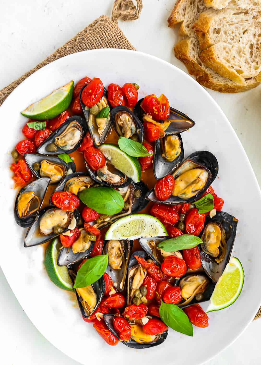 baked mussel with tomatoes, and cappers in a oval white plate