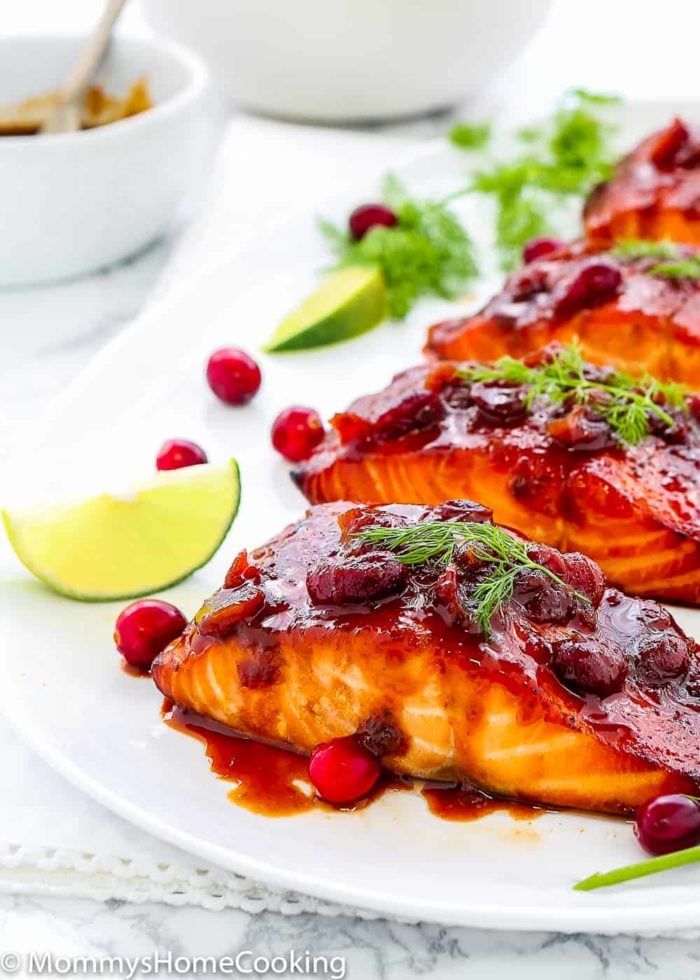 Salmon with Cranberry Honey sauce in a white plate with lemon wedges