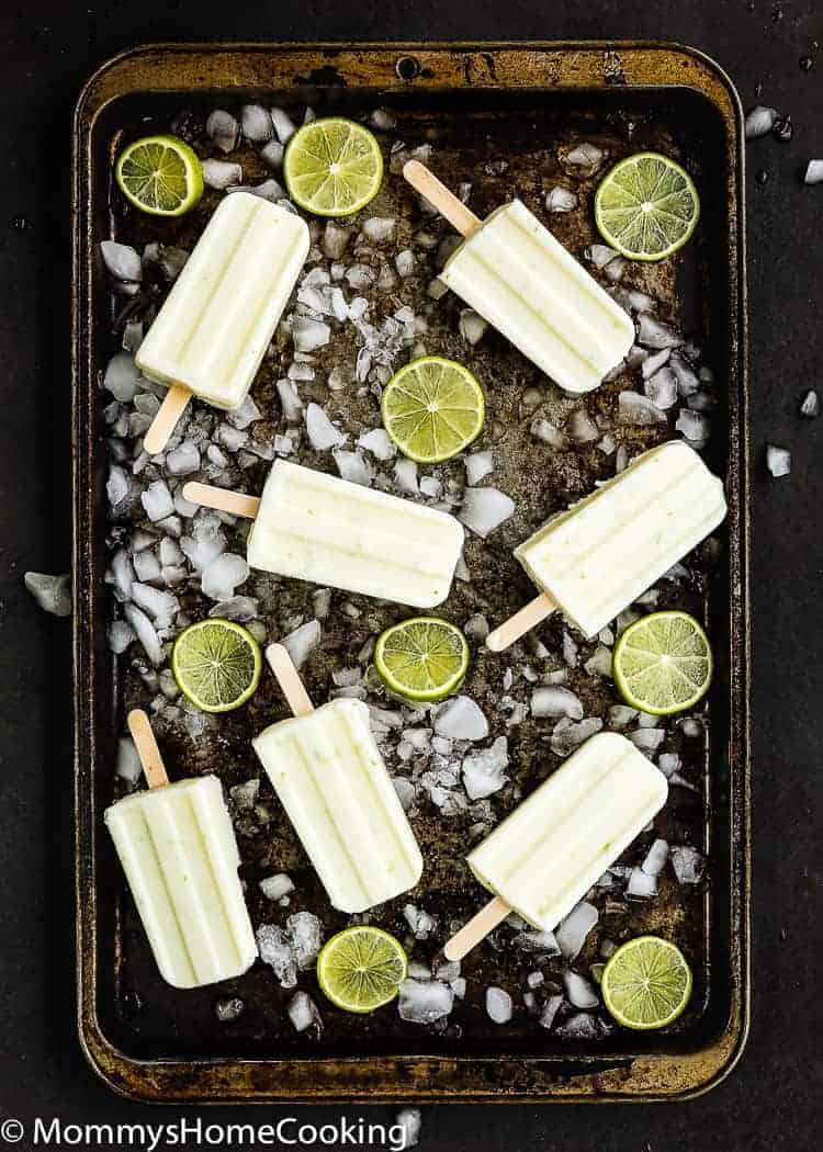 overhead view 3-Ingredient Key Lime Popsicles in a baking tray with ice and lime slices