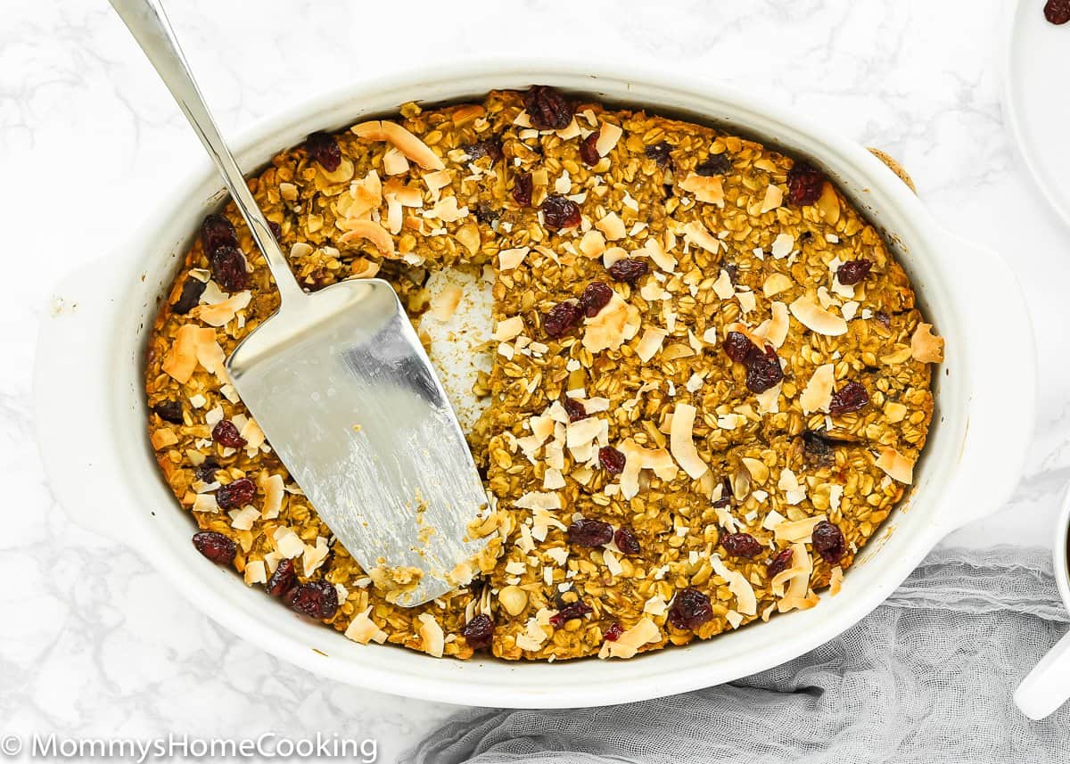 Eggless Baked Oatmeal in a baking dish with a serving spatula.