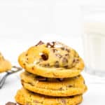 Eggless Chocolate Chip Cookies with sea salt stack with a glass of milk in the background