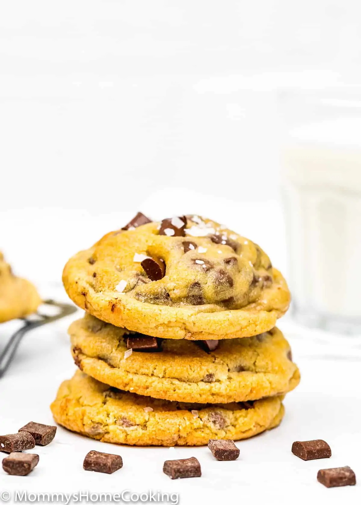 Eggless Chocolate Chip Cookies with sea salt stack with a glass of milk in the background