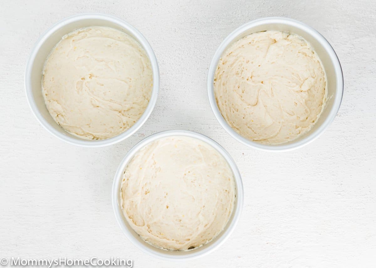 three cake pans with eggless vanilla cake batter inside