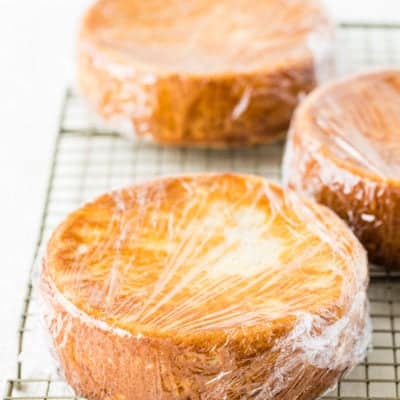 three eggless vanilla cakes wrapped in plastic wrap
