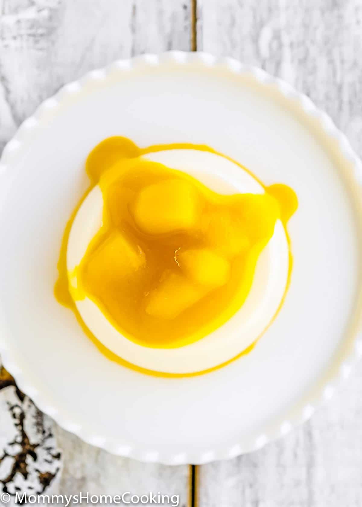 overhead view of a Mango Panna Cotta with mango sauce on a plate.