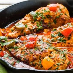 Creamy peri-peri chicken in a pan with sauce and peppers.