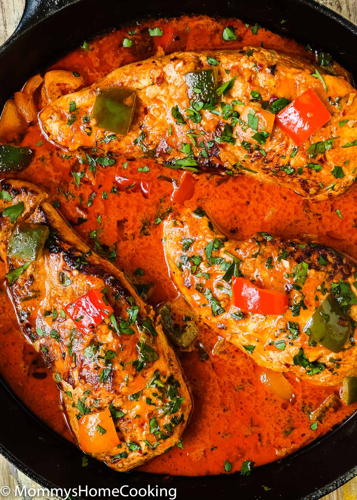 Chicken in a pan with peri-peri cream sauce and peppers.