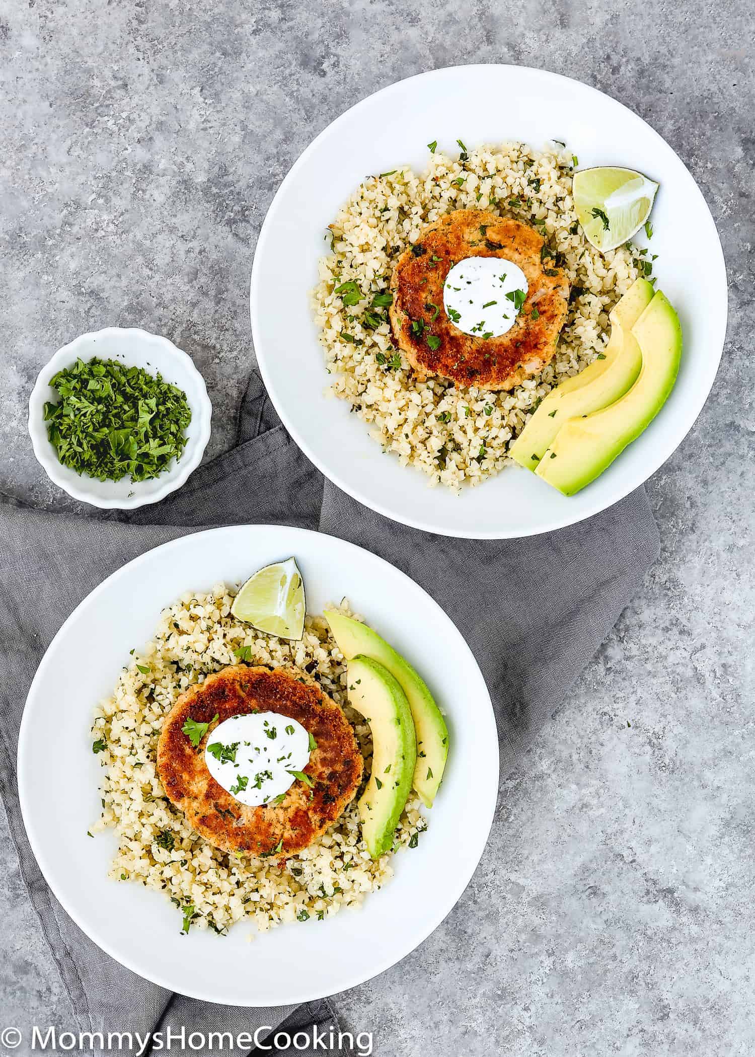 Two plates with Eggless Salmon Patties, Cauliflower rice and avocado.