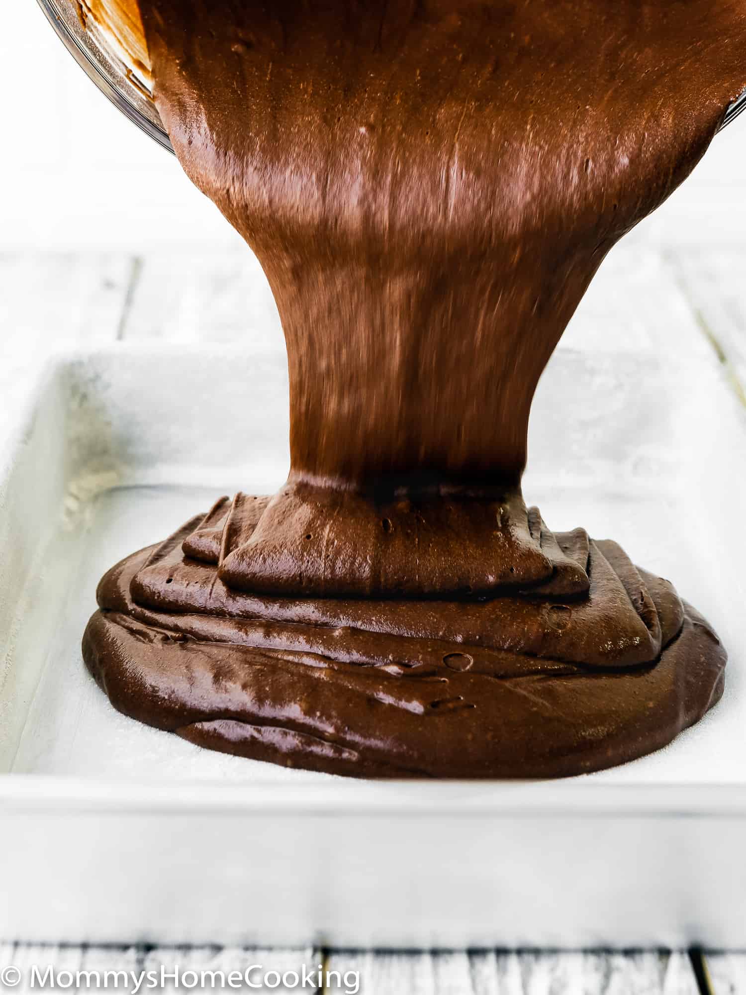 Cake batter being poured into a greased pan.