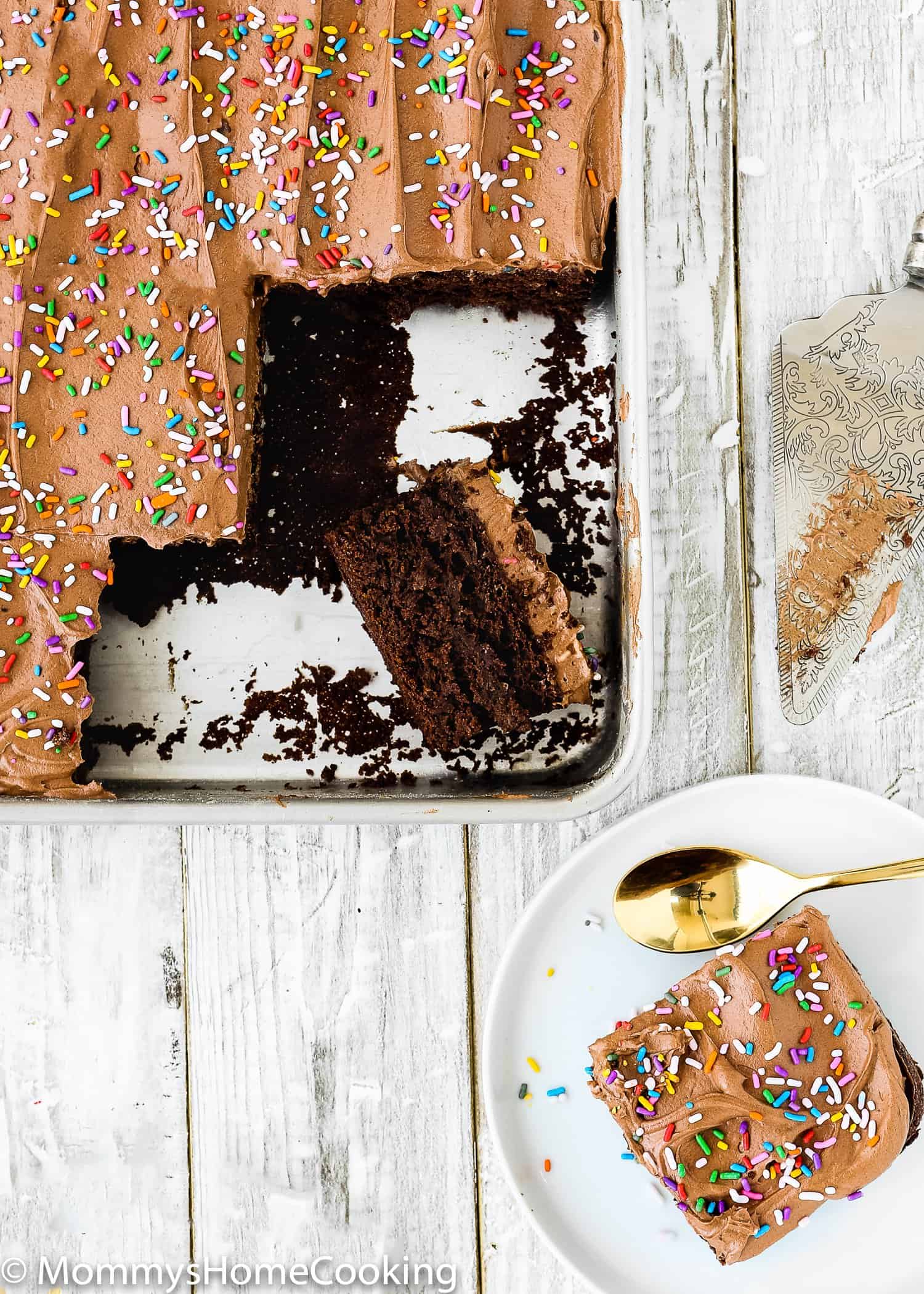 A tray of chocolate cake with a slice on a plate beside it.