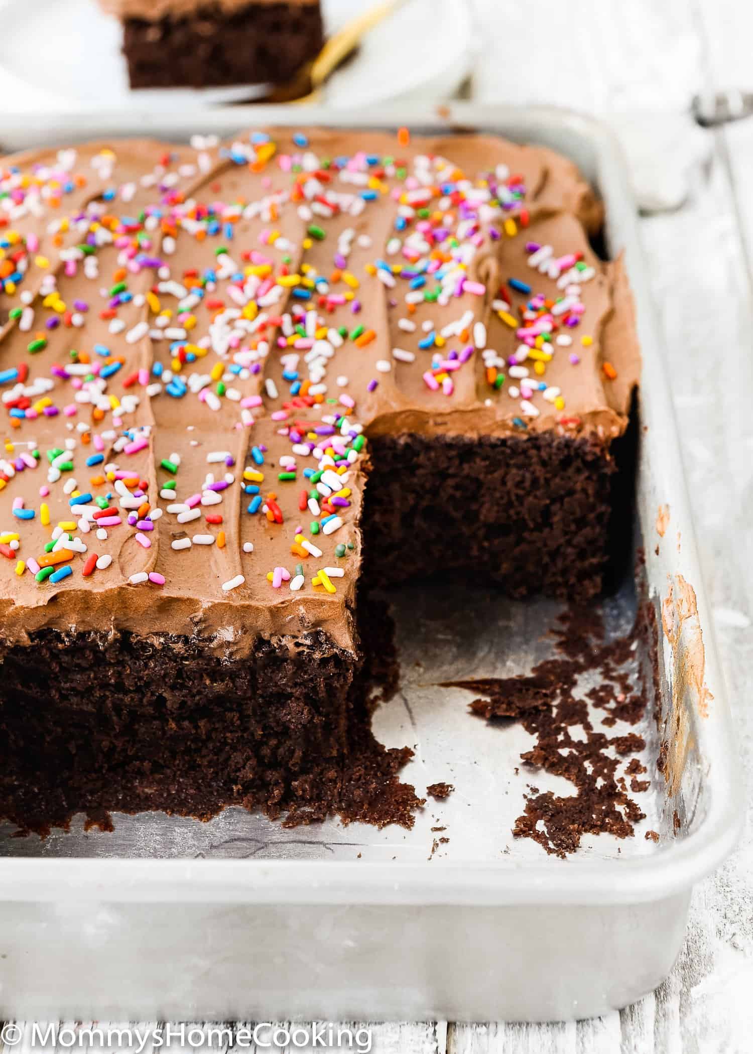 A pan of egg-free chocolate cake with slices cut out.