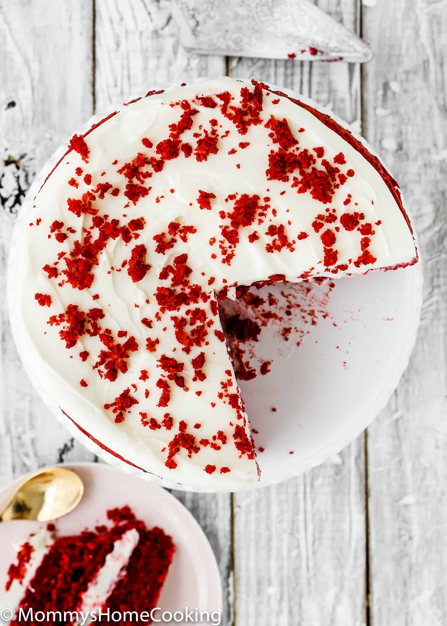 Overhead view of a sliced red velvet cake with cream cheese frosting.