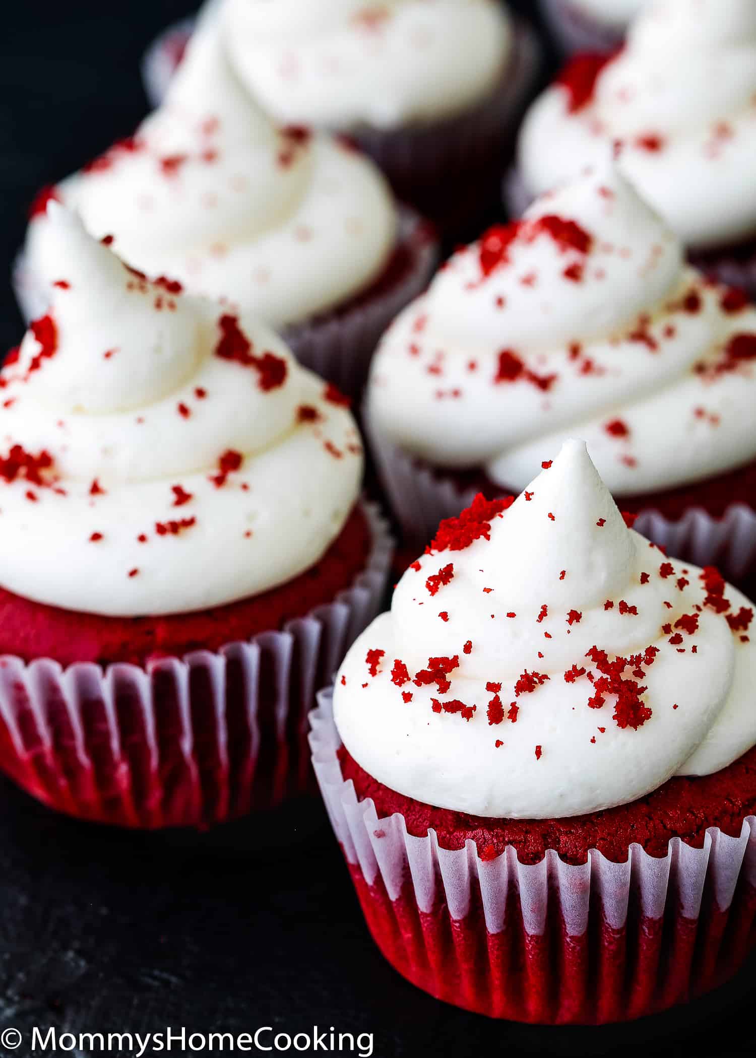 egg-free red velvet cupcakes with frosting over a black surface