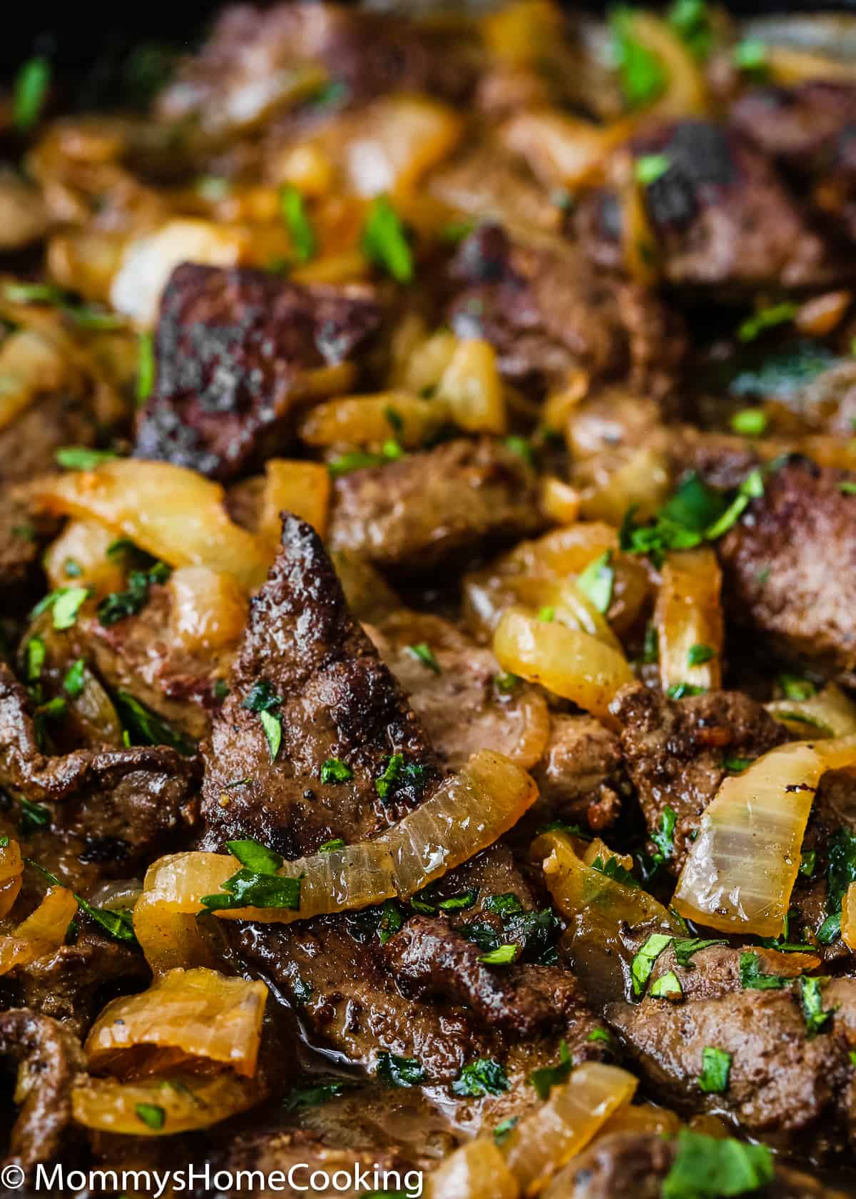 close up of beef liver and onion in a skillet garnished with chopped cilantro