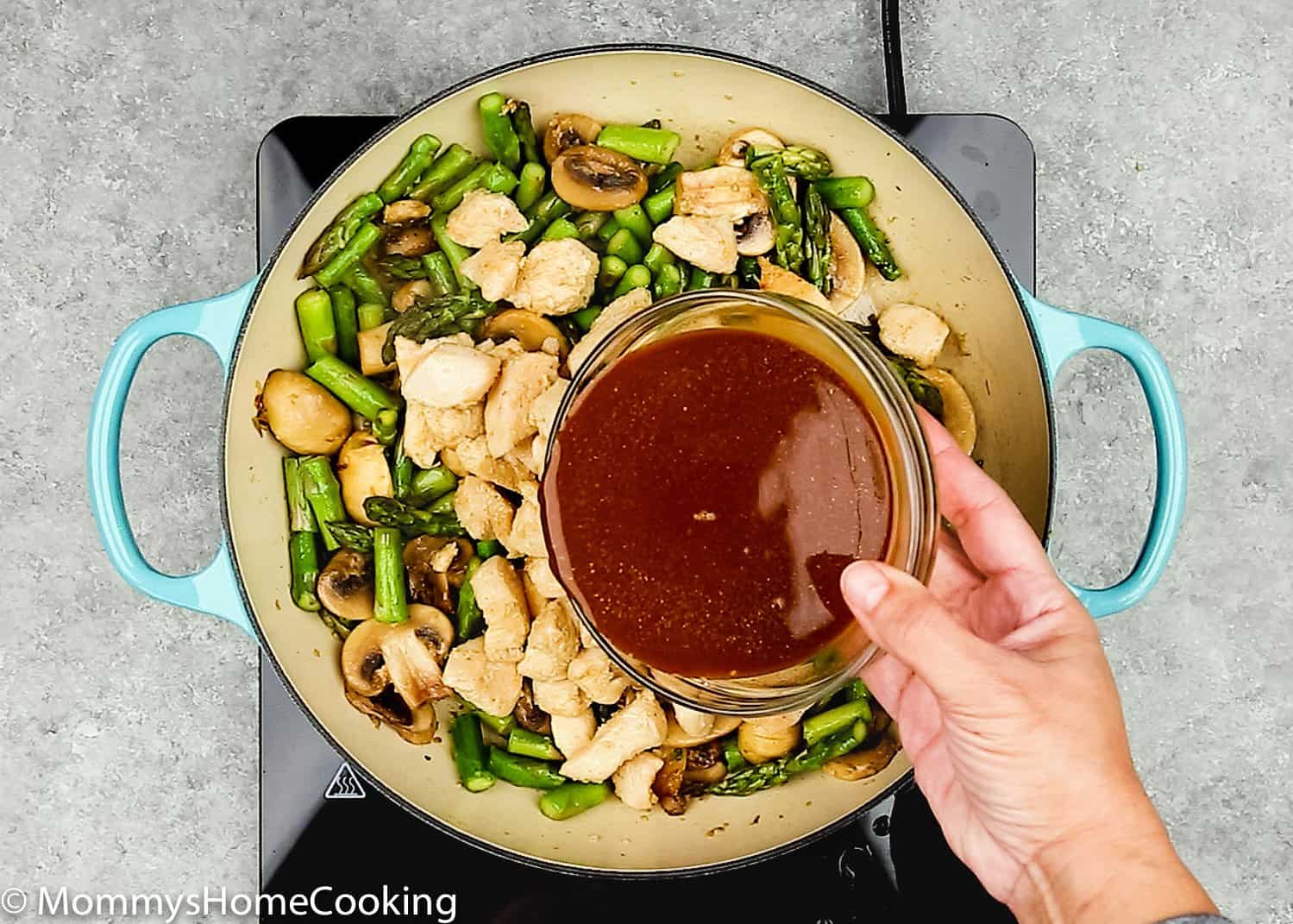 a hand holding a bowl with sauce for healthy chicken 