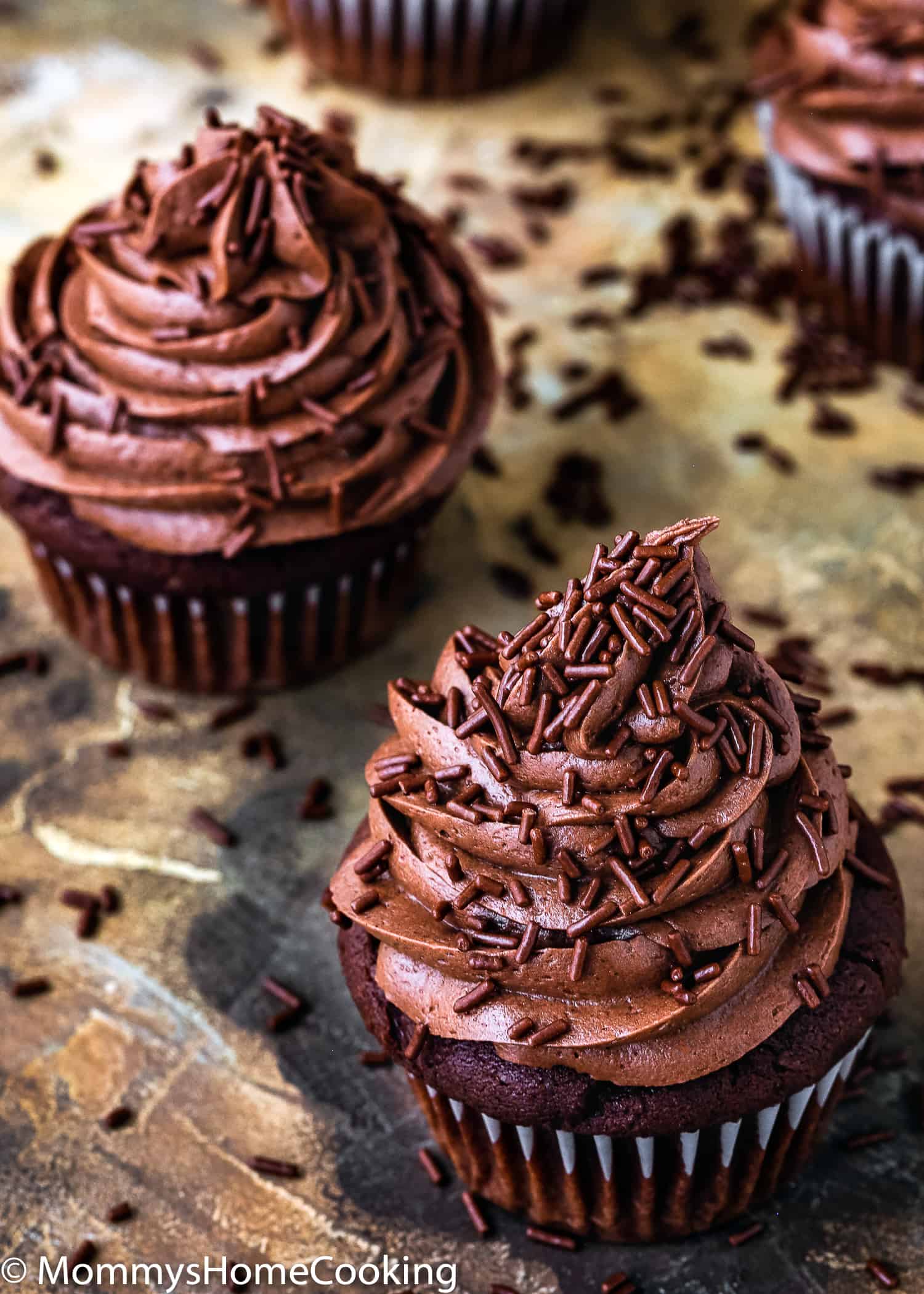 Eggless chocolate cupcakes with chocolate frosting and sprinkles.