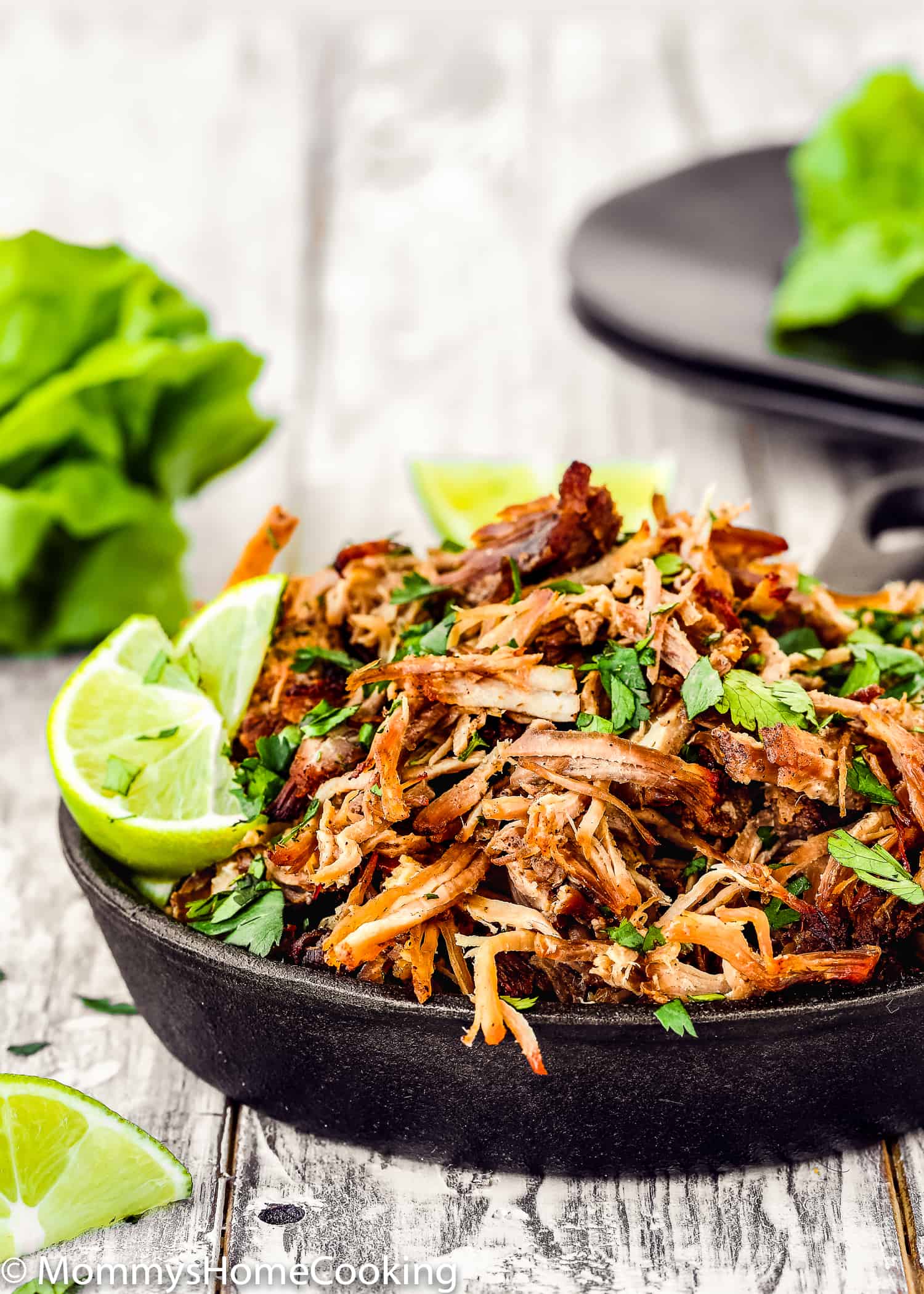 pork carnitas in a mini skillet with lemon wedges and cilantro.