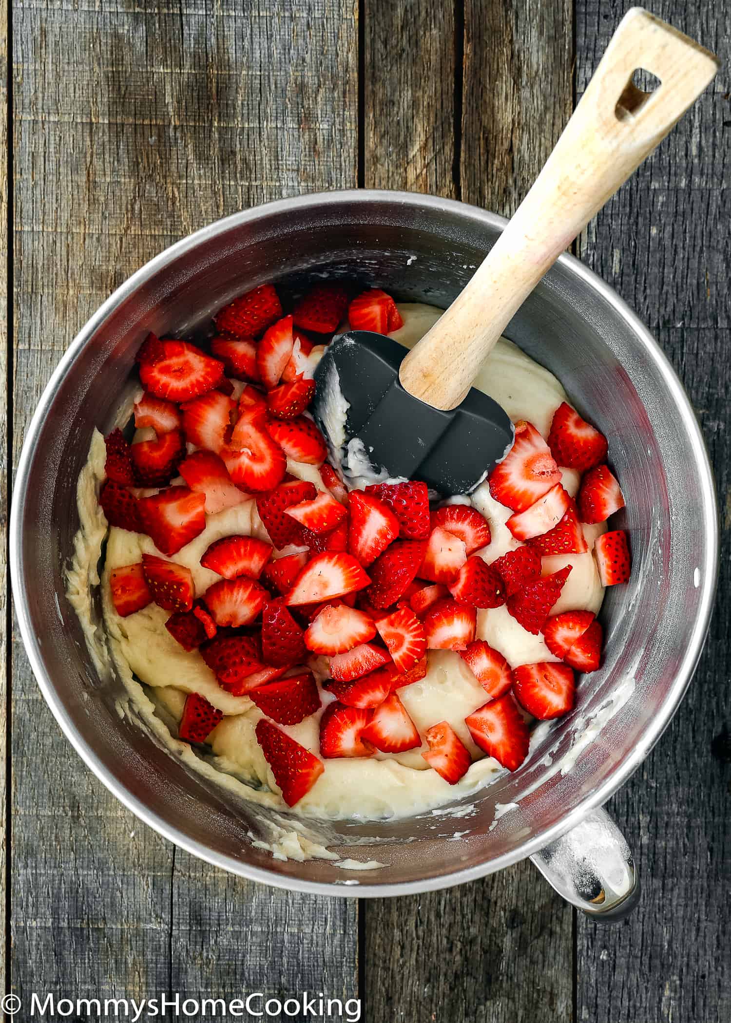 eggless strawberry cake batter with chopped fresh strawberries in bowl with a spatula.