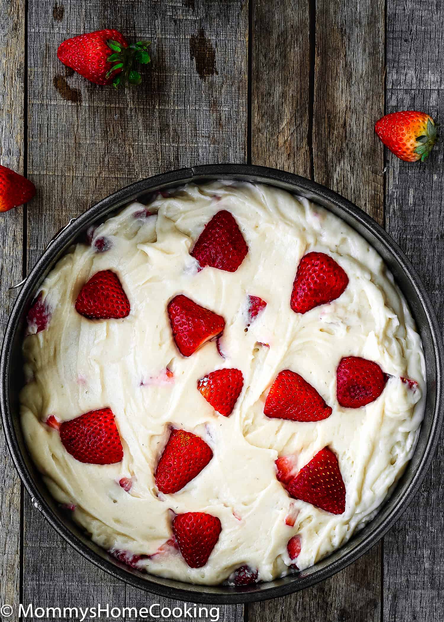 eggless strawberry cake batter with chopped fresh strawberries on top in a springform pan.