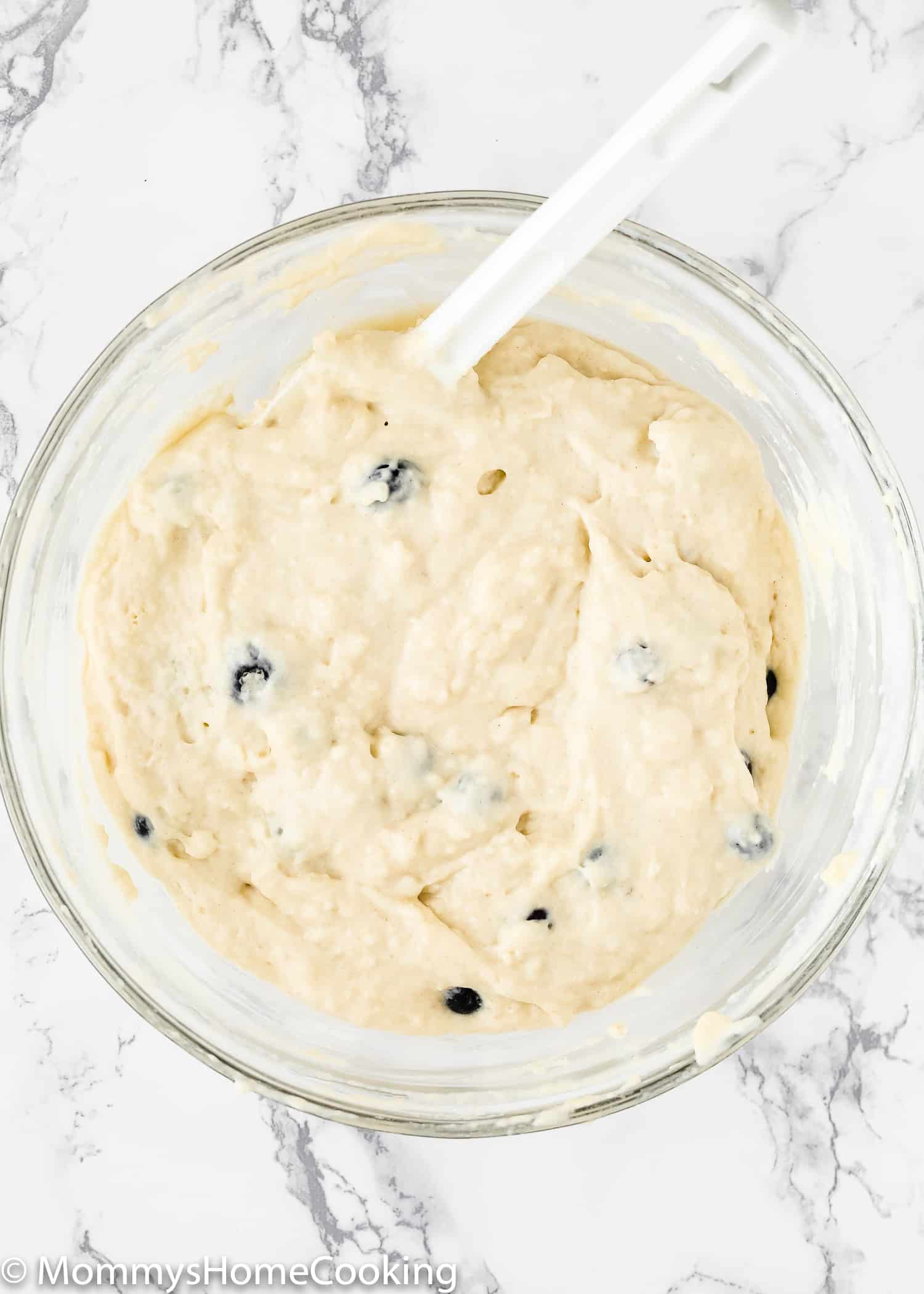 Eggless Blueberry Muffins batter in a bowl with a spatula.