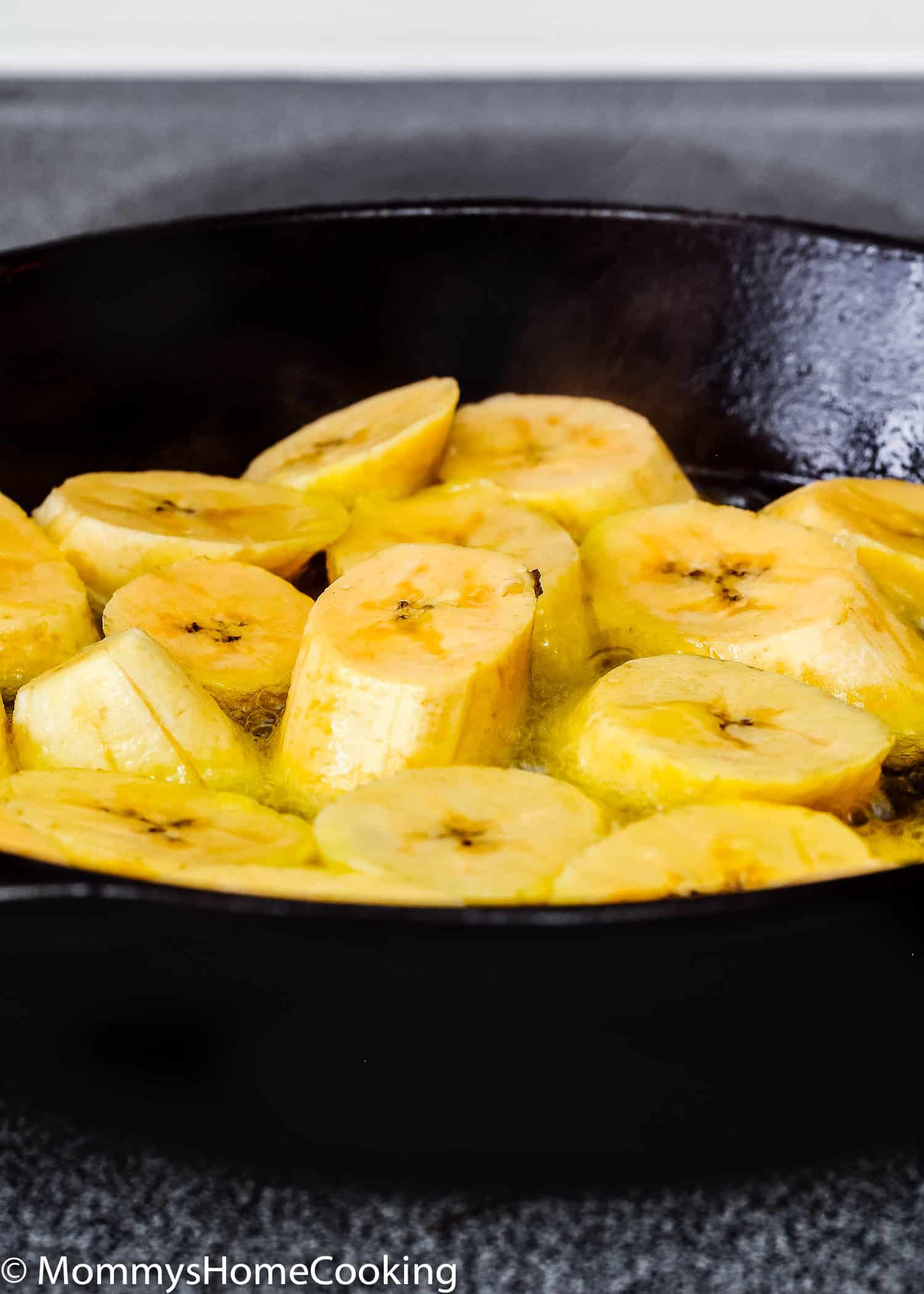 ripe plantains in a skillet being cooked.