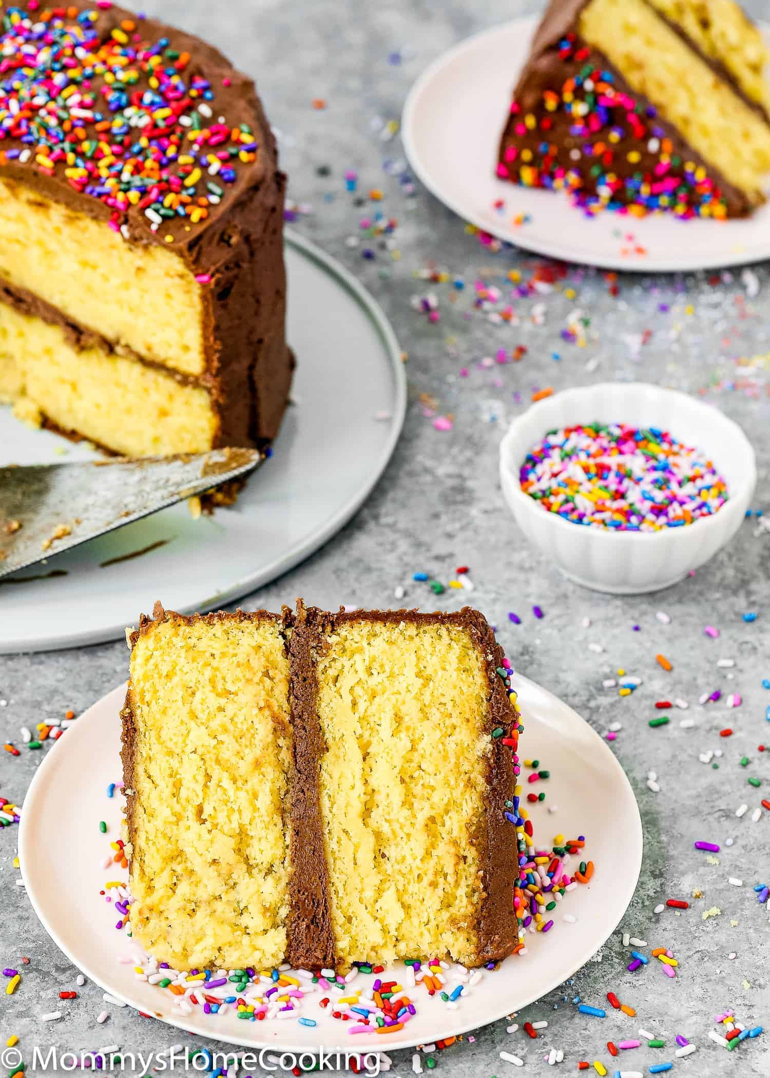 A slice of box cake in a plate with chocolate frosting and sprinkles.