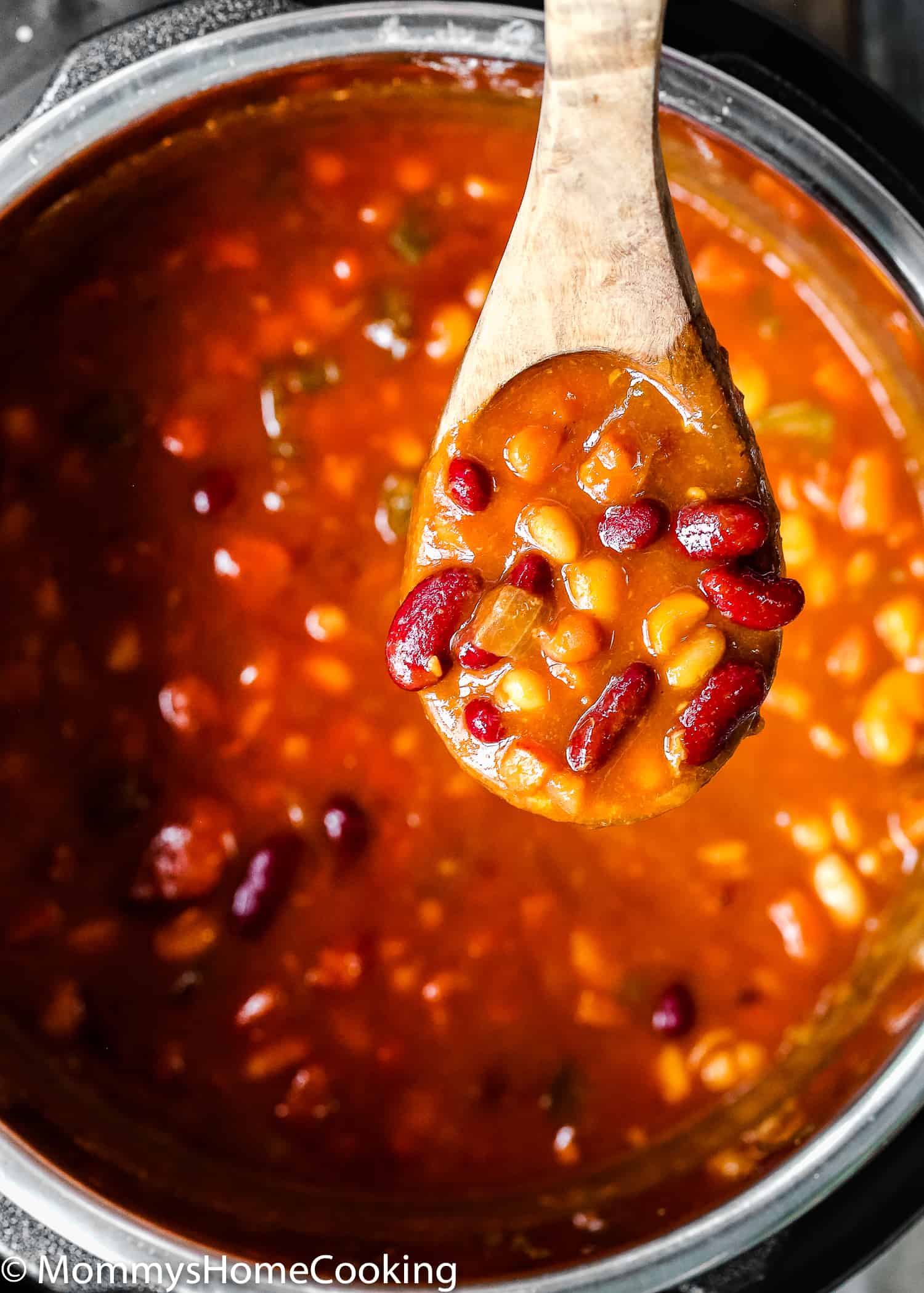 a wooden spoon with Instant Pot Baked Beans.