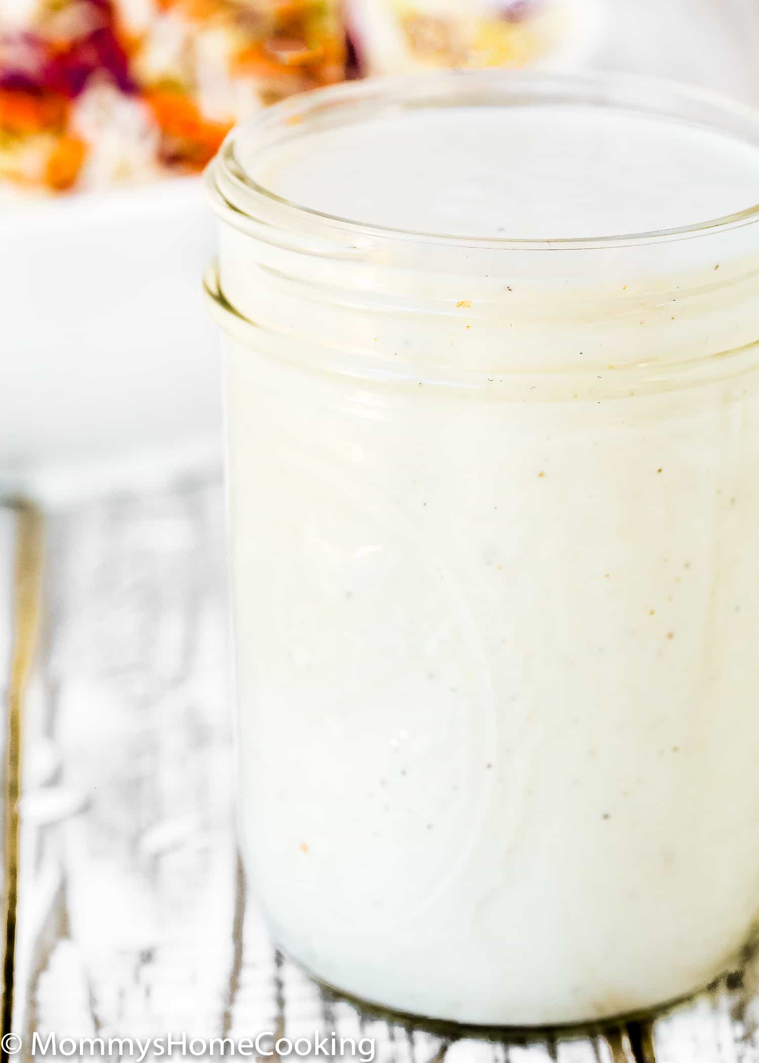 homemade buttermilk salad dressing in a mason jar with a coleslaw salad in the background. 