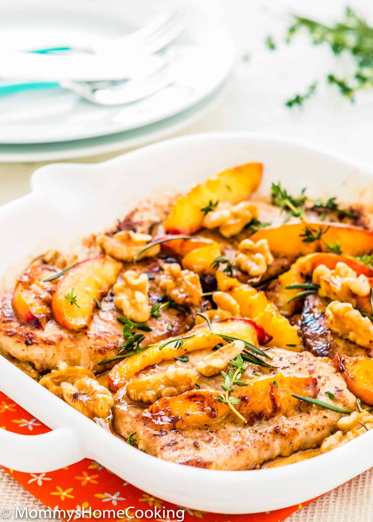 grilled pork chops and peaches with herbs in a skillet