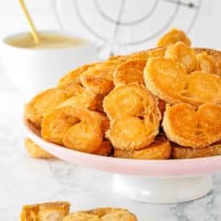 Easy Palmiers cookies in a pink cake stand with a cup of coffee in the background.