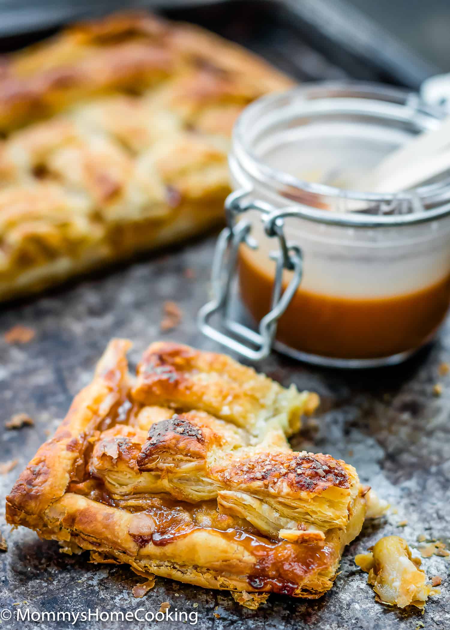 a portion of Eggless Salted Caramel Apple Cheese Danish with salted caramel jar in the background.