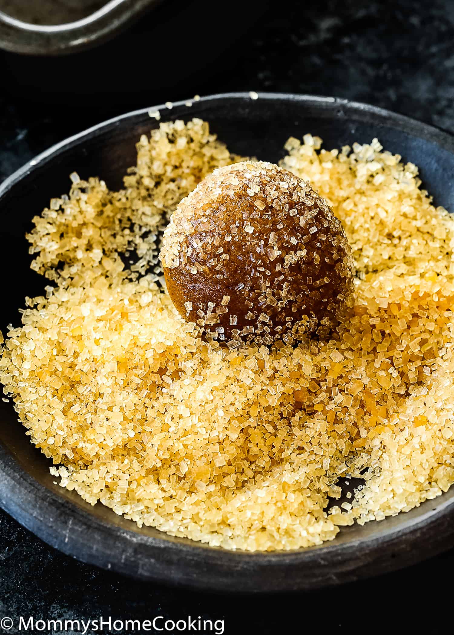 Egg-free Molasses Cookie dough ball rolled with raw sugar