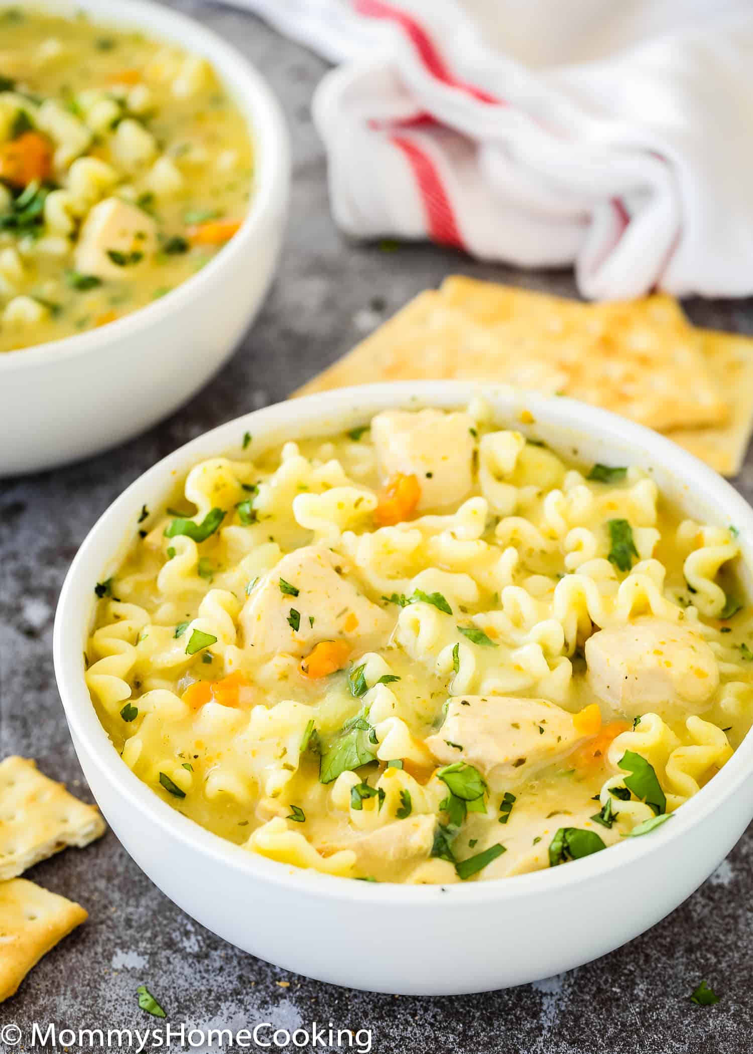 two bowls of Creamy Chicken Noodle Soup garnished with cilantro.