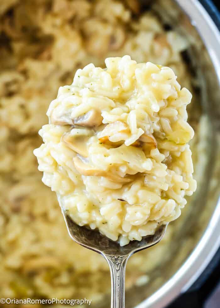 a spoon with Instant pot risotto that is creamy and silky.