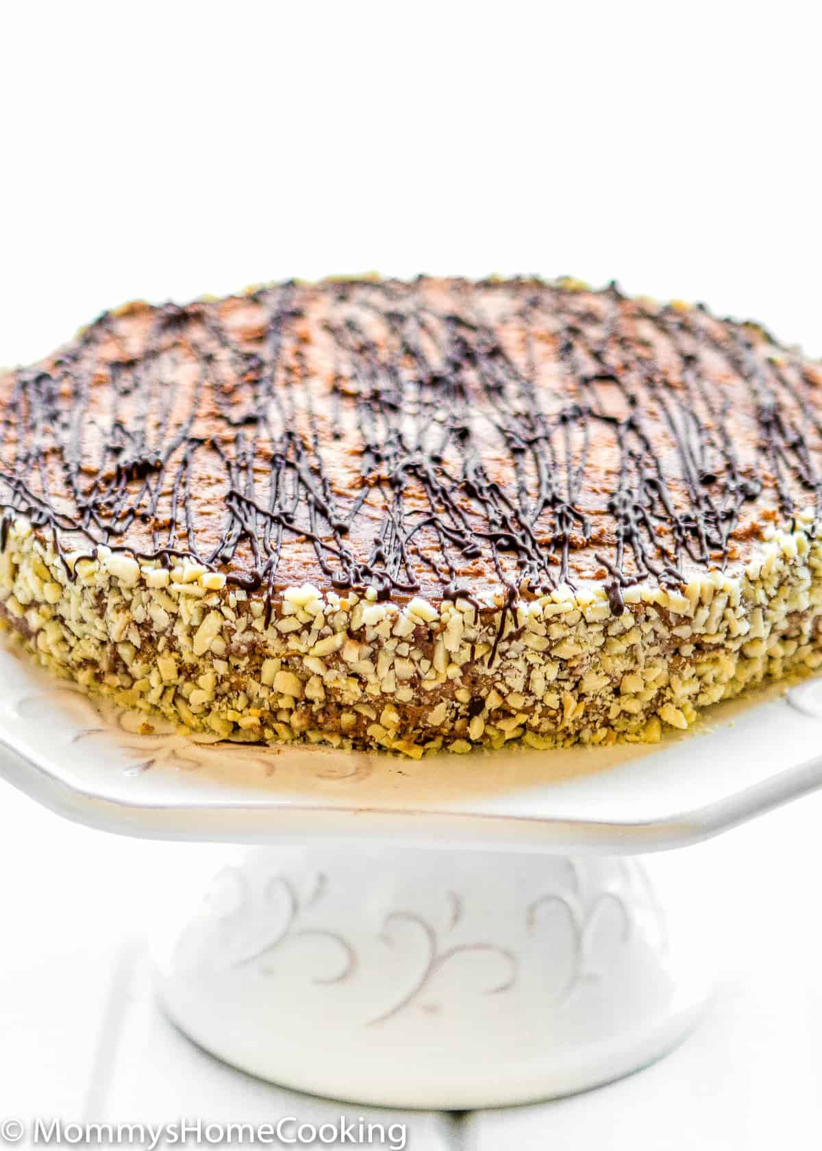 Venezuelan Chocolate Marquesa with chocolate drizzle and chopped nuts on a cake stand