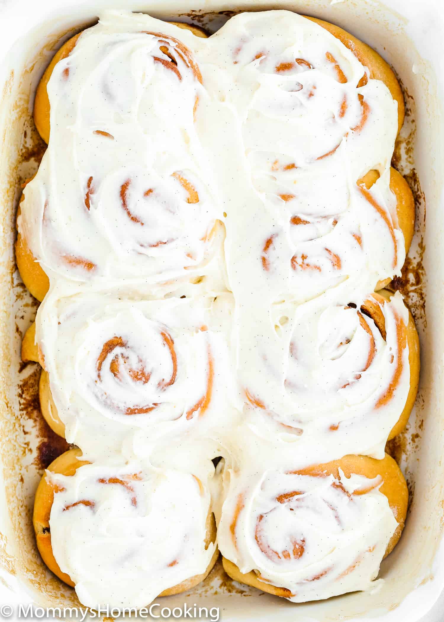 Egg-free cinnamon rolls in a baking pan with frosting on top.