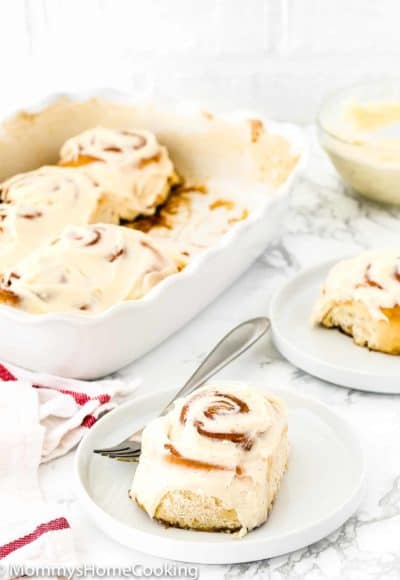 eggless cinnamon roll with frosting on a plate with a fork on the side