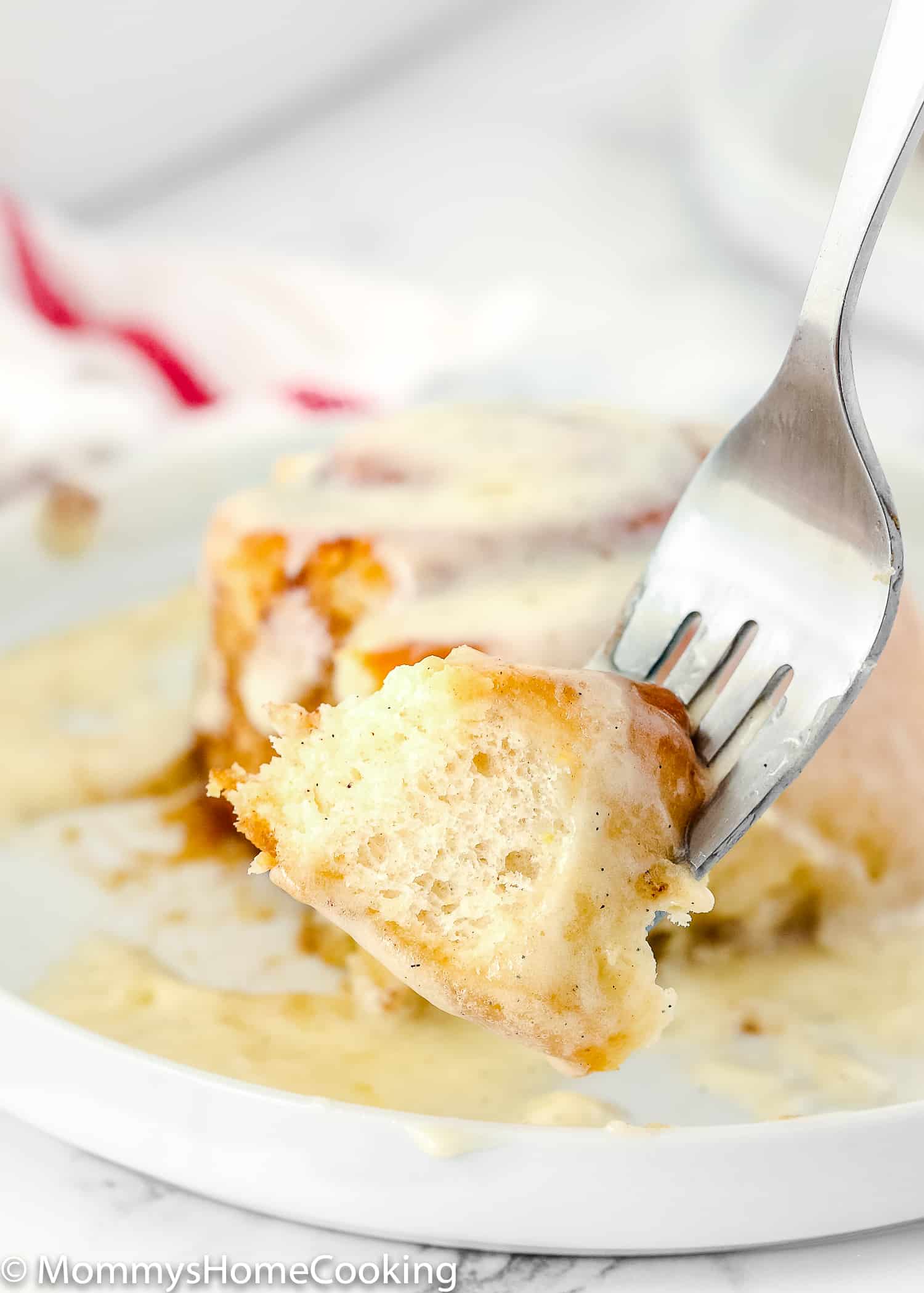 a fork holding a piece of egg-free cinnamon roll with frosting