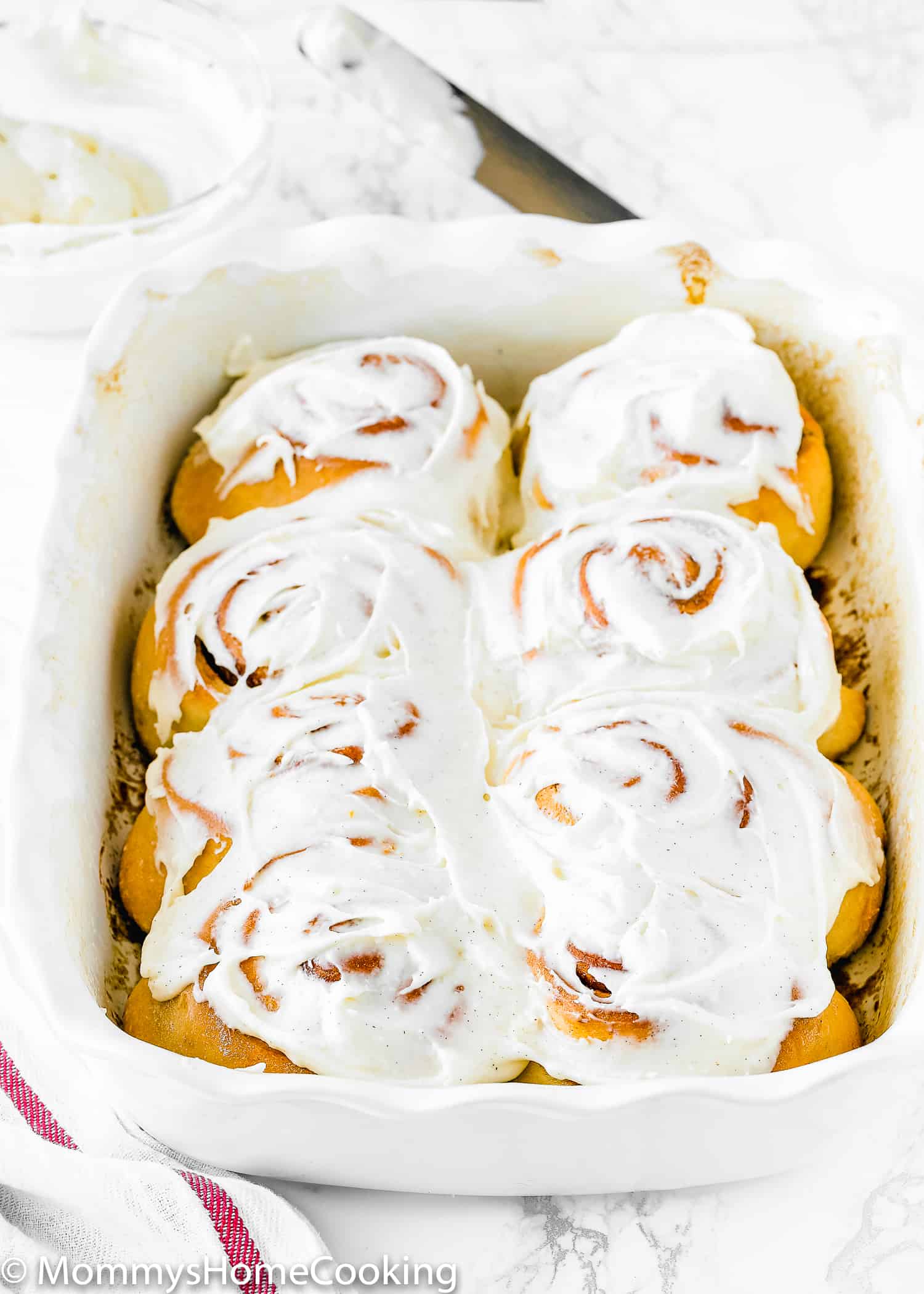 egg-free cinnamon rolls in a baking pan with frosting on top