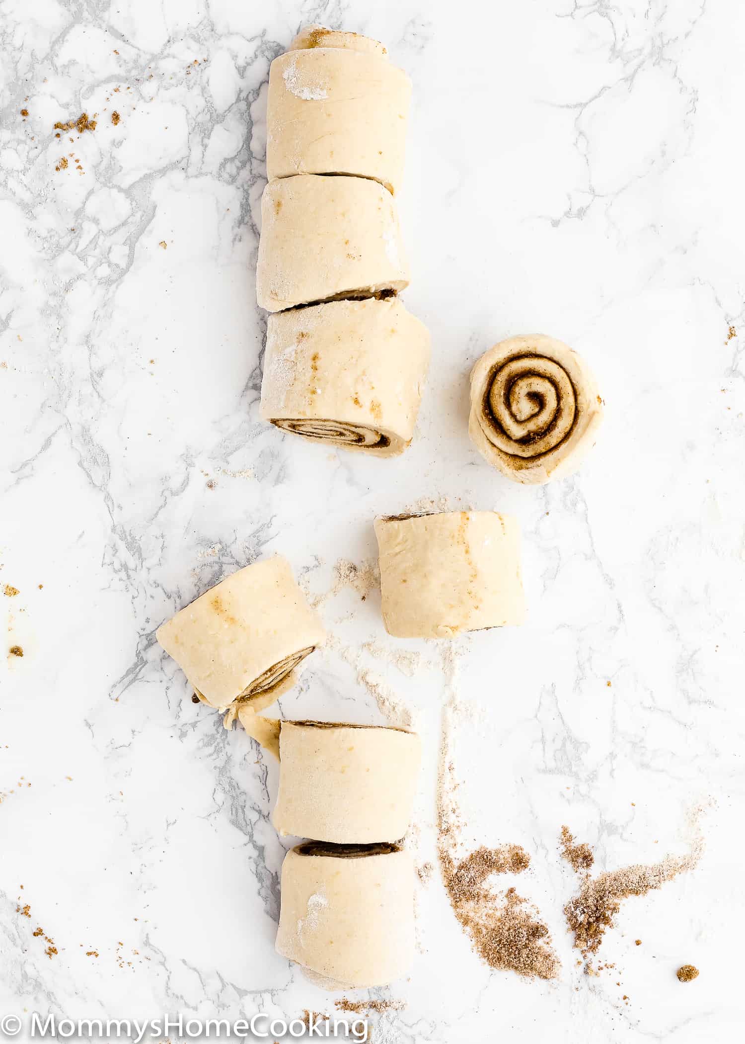 Egg-free cinnamon roll dough rolled out into a log and cut into 8 pieces. 